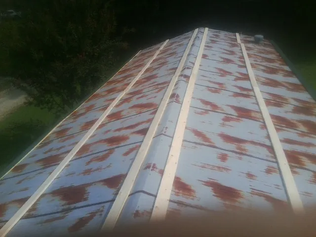 Rusted metal roof panels with new wood purlins before replacement — Storm Damage Roof Repair in South Jamesport by Roofing Brothers