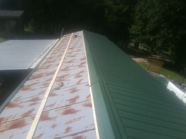 Old rusted panels beside newly installed green metal roofing — Wind Damage Roof Repair by Roofing Brothers in South Jamesport
