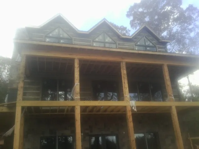 Dormers and porch framing on a large log home under construction — Roof Coating work by our crew in South Jamesport