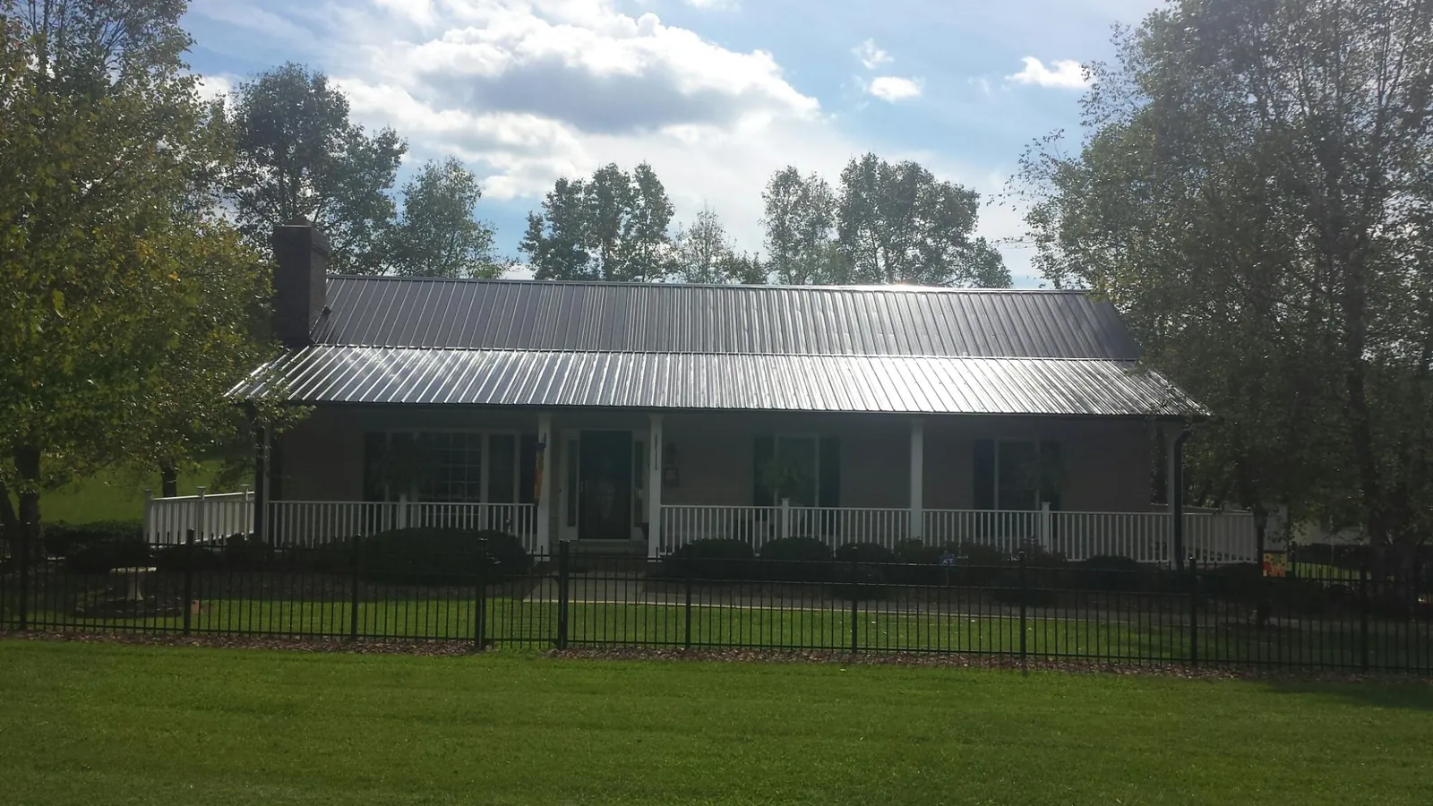 Gray metal roof on a brick ranch with a full width front porch — Gutter Guard Installation work by our crew in South Jamesport