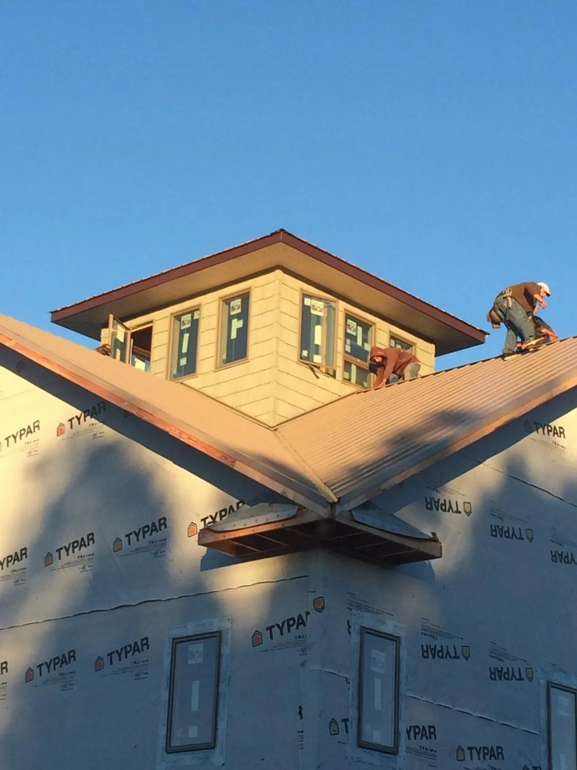 Roofers working around a rooftop cupola on a new metal roof at sunset — Roof Waterproofing in South Jamesport by Roofing Brothers